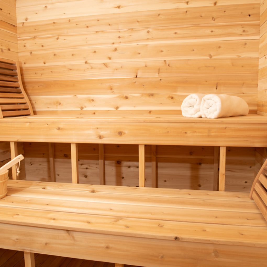 A luxurious Dundalk Canadian Timber Luna 2 to 3 Person White Cedar Sauna made of Eastern White Cedar, complete with towels and a soothing ambiance.