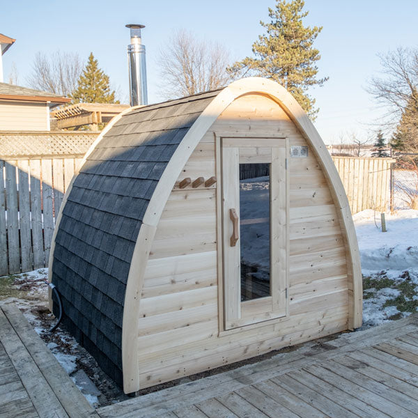 A serene retreat featuring a Dundalk Canadian Timber CT MiniPOD Sauna by Dundalk LeisureCraft nestled on a rustic wooden deck.
