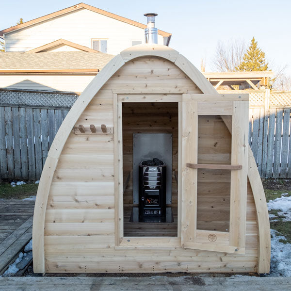 A Dundalk LeisureCraft Canadian Timber CT MiniPOD Sauna retreat in the backyard, with an open door.