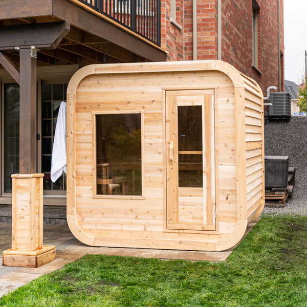 A luxury Dundalk LeisureCraft Luna Sauna made of Eastern White Cedar, constructed with exquisite Dundalk Canadian Timber Luna 2 to 3 Person White Cedar, is nestled in the backyard of a house.