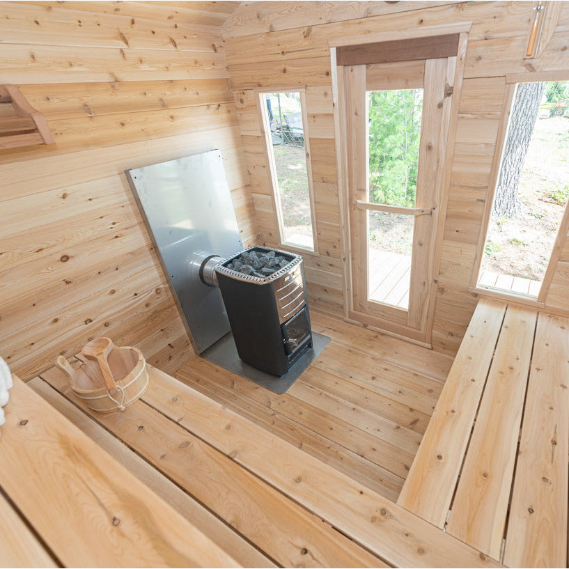 The inside of a Luxury Dundalk Canadian Timber Georgian Cabin Sauna with Eastern White Cedar walls and a wood stove, making it the perfect backyard Recovery Space. (Brand Name: Dundalk LeisureCraft)