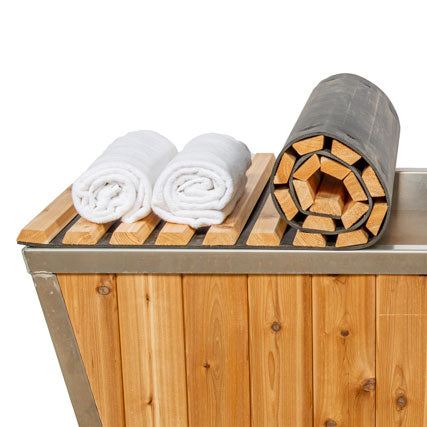 A Dundalk LeisureCraft wooden hot tub with towels on top of it, featuring a Dundalk LeisureCraft Roll Up Cover - Knotty 32-1/4"x70".