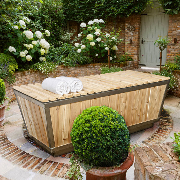 A Dundalk LeisureCraft The Polar Plunge Tub in a garden, ideal for enjoying the serene atmosphere and relaxing amidst nature.