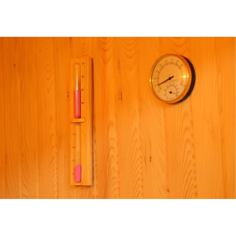 A SunRay Saunas wooden wall adorned with a thermometer and a clock.